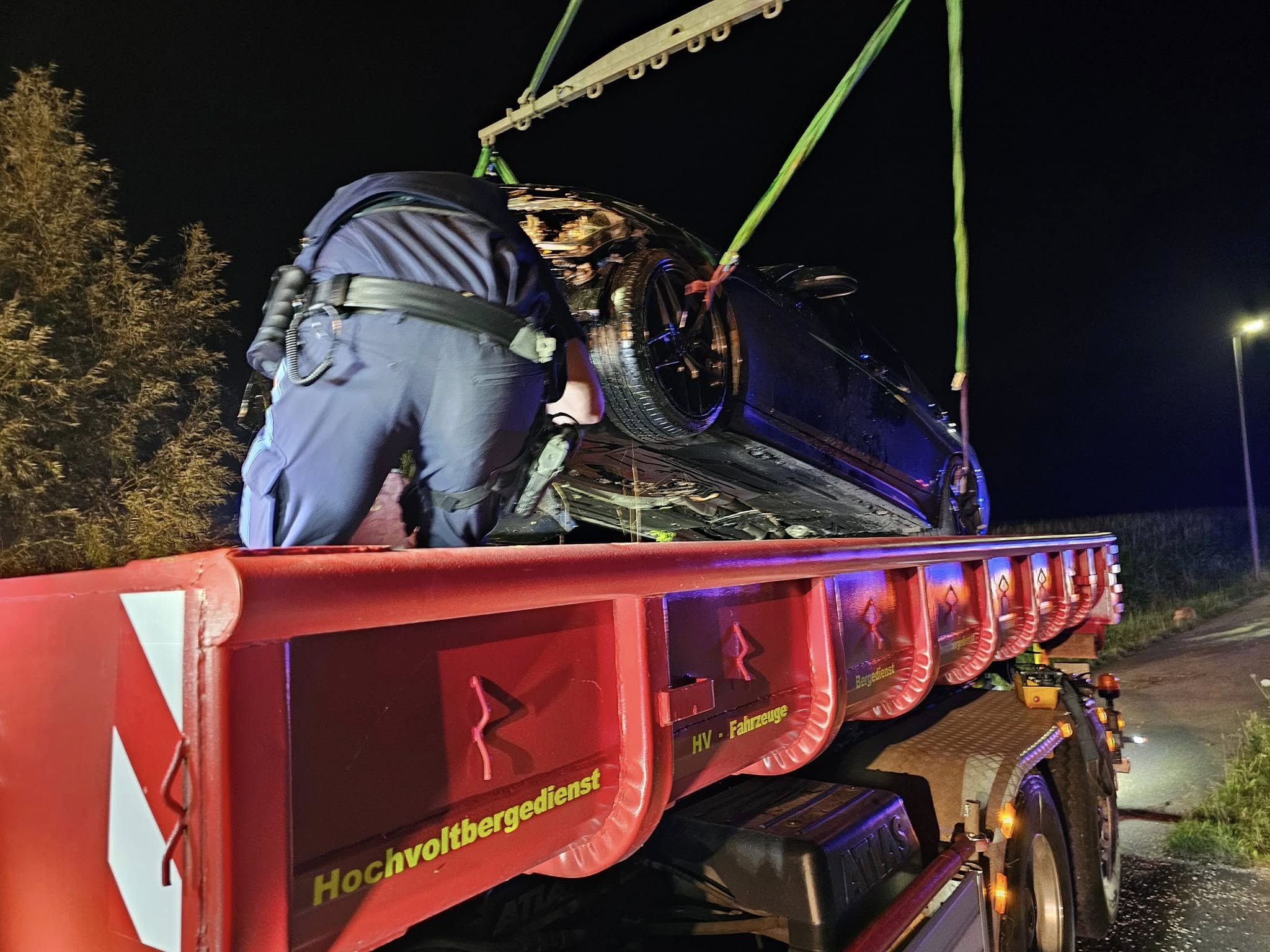 Hochvoltbergung bei Nacht — Unfallwagen wird mit Krangurten auf Bergefahrzeug gesichert